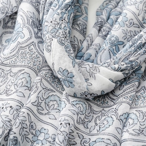 Detailed close-up of blue and white paisley patterns on soft cotton-linen scarf fabric