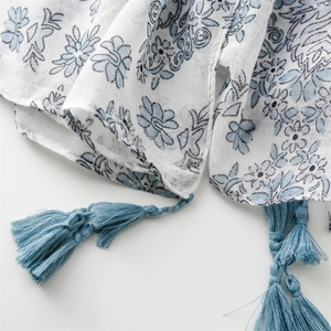Detailed view of light blue floral print scarf with delicate fringe on soft fabric