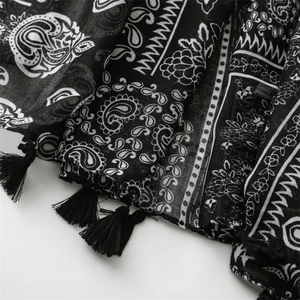 Detail of lightweight paisley pattern scarf showing black tassels and sheer texture