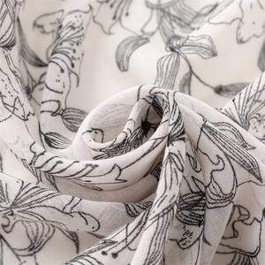 Vue macro d'un foulard léger avec motifs de feuilles noires sur fond blanc pur