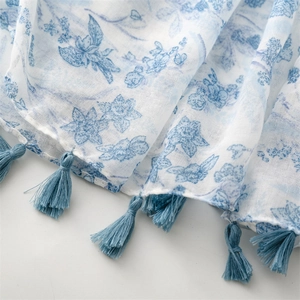 Detail of light blue floral print scarf showing breathable fabric and tassel trim