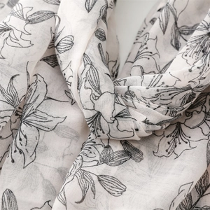 Détail macro d'un foulard en coton-lin respirant avec d'élégants motifs floraux noirs