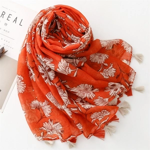 Close-up of orange floral scarf featuring linen texture and delicate fringe trim details