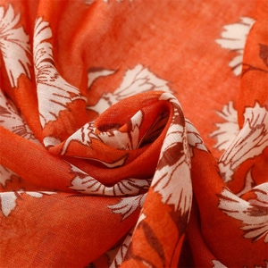 Close-up of orange linen-feel scarf with white floral patterns and detailed fabric texture