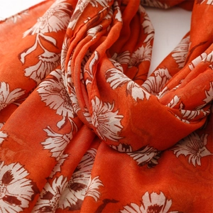 Detailed macro view of orange floral print on lightweight linen-feel scarf fabric