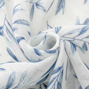 Close-up of white linen-feel fabric with blue leaf prints and delicate tassel detail