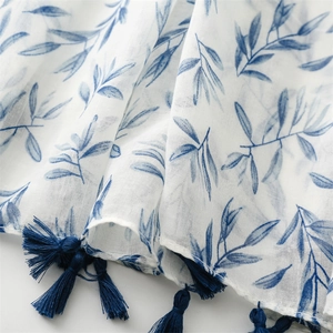 Detailed view of the linen texture with blue floral print and fringe tassels