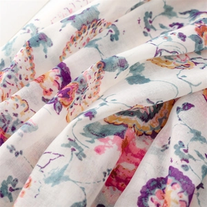 Macro shot of colorful floral pattern on light cotton linen scarf with tassels