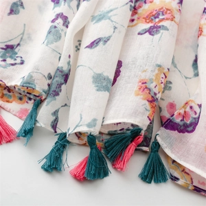 Detailed macro view of floral print and woven colorful tassels on a linen cotton scarf