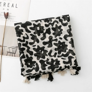 Detail of black and white floral linen scarf with tassel fringe and abstract pattern