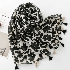 Detail of a lightweight black and white floral scarf with stylish fringe tassels and textures