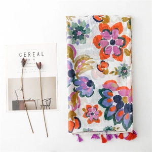 Linen feel cotton scarf with colorful floral print and tassel trim on white background