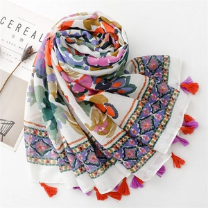 Detail of bohemian scarf with floral prints and colorful handmade tassels on white fabric