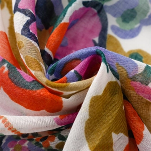 Macro detail of watercolor floral print fabric with soft cotton-linen texture and tassels