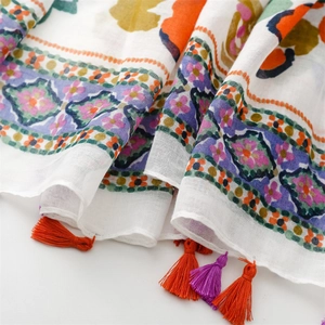 Detailed texture of bohemian floral print scarf with vibrant orange and purple tassels