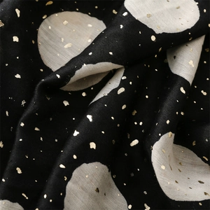 Detailed close-up of black scarf fabric with beige polka dots and golden foil accents