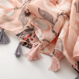 Dettaglio di sciarpa in lino con stampa floreale rosa, trama a spina di pesce e nappe