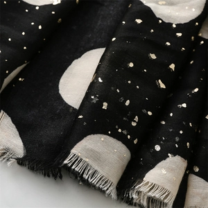 Detail of soft scarf featuring black and white polka dots with gold foil and fringe edges