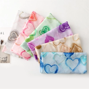 Detail view of cotton-linen scarves with gold-trimmed watercolor heart patterns in 6 colors