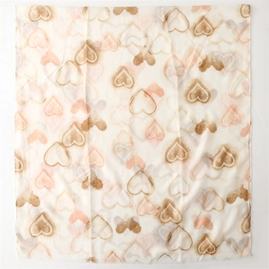 Detail of soft cream scarf featuring elegant gold-trimmed pink heart prints and texture