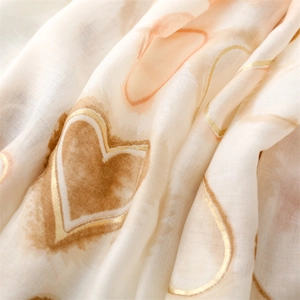 Detail of soft scarf fabric showing watercolor heart patterns with gold foil accents