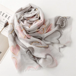 Detail of soft heart pattern scarf with gold foil accents and fringe edges on white background
