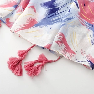 Detail of artistic abstract print shawl with pink multi-layer tassels and gold accents