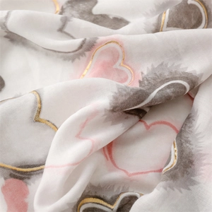 Detail of soft white scarf with pink and grey hearts featuring gold metallic outlines