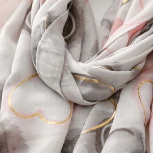 Detailed close-up of white scarf with golden heart prints and pink floral patterns