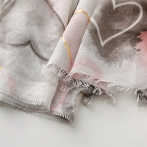 Detailed close-up of gray and pink scarf featuring gold foil heart prints and fringe edges