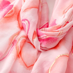 Detail of pink cotton linen scarf featuring romantic gold foil heart patterns and soft texture