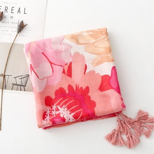 Detail of soft cotton scarf with vibrant red floral print and pink fringe tassels