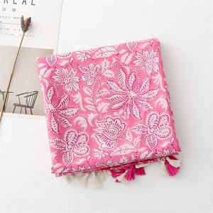 Close-up of bright pink cotton linen scarf with white floral prints and fringe tassels