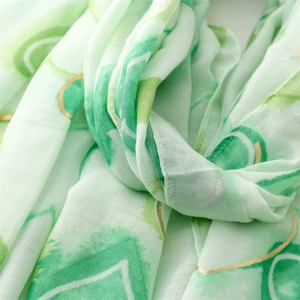 Detail of green watercolor scarf with golden outlines on soft semi-transparent fabric