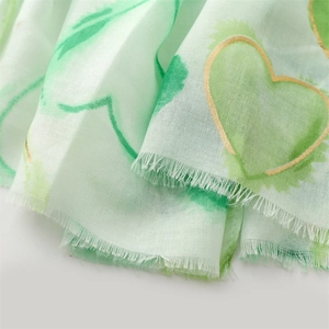 Close-up of mint green heart prints with gold foil edges and fringe detail on scarf