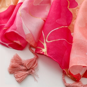 Detail of red floral scarf showing twill texture, golden lines, and woven tassels