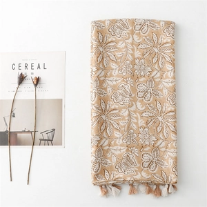 Flat lay of linen scarf with white floral patterns and fringe next to a magazine