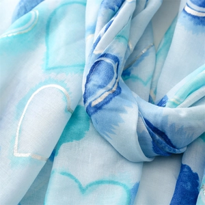 Detail of light blue cotton-linen scarf featuring silver foil heart pattern and soft texture