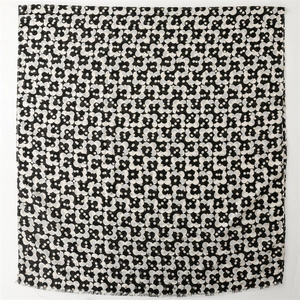 Detail of elegant black and white floral scarf with gold polka dots and frayed edges