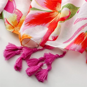 Detail of vibrant tropical floral print on soft scarf with pink fringe tassels