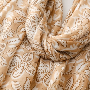 Close-up of floral leaf print on beige cotton-linen scarf fabric with natural folds