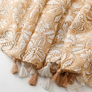 Detailed view of floral print linen scarf with dual-tone decorative tassel edges