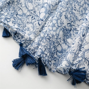 Detailed view of blue floral print fabric with thick navy blue decorative tassels
