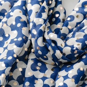 Close-up of blue floral cotton linen scarf with elegant gold foil polka dots texture