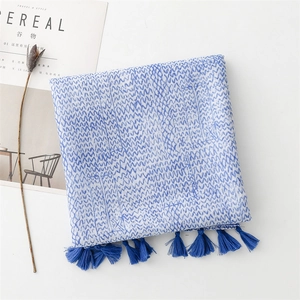 Detail of blue and white wavy print scarf with blue tassels on a minimal background