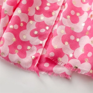 Detailed close-up of pink floral scarf with gold foil dots and raw fringe edge