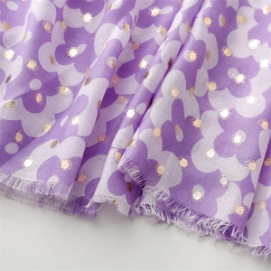 Detailed view of floral pattern scarf with gold foil dots and raw fringe edges