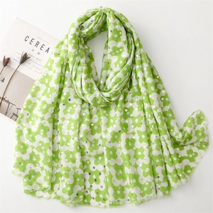 Detailed view of green floral scarf with gold dots and frayed edges beside a magazine