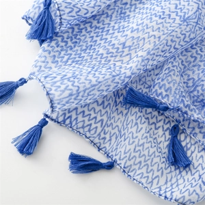 Detail view of cotton linen scarf with blue wavy line patterns and tassel fringe edge