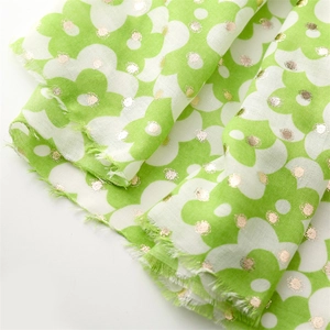 Detail of green scarf with white flower patterns and golden foil dots with fringe